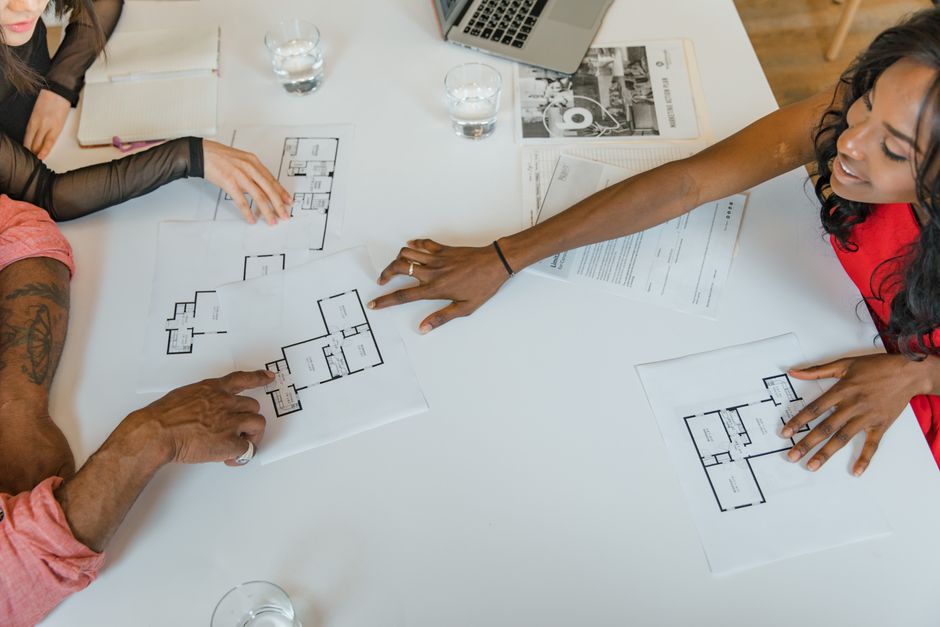 High angle view of diverse business team discussing architectural plans around a table.